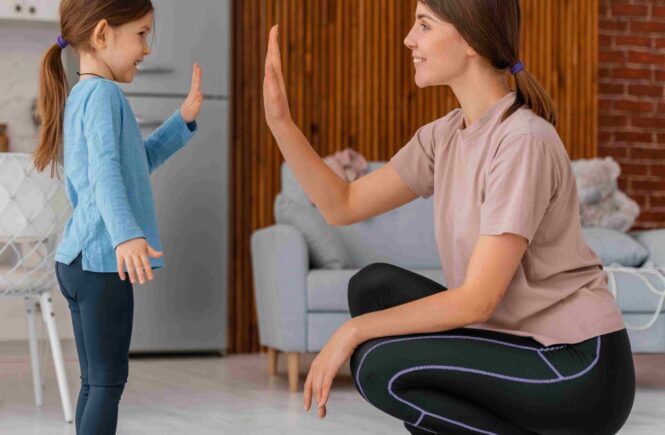 Mother and young daughter smiling and giving each other a high-five indoors during a playful bonding activity.